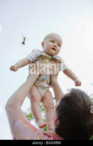 Baby girl being lifted by father Stock Photo