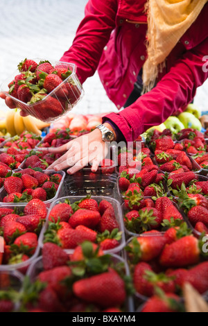 Close-up mid section of woman choosing strawberries at fruit market Stock Photo