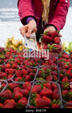 Close-up mid section of woman paying for basket of strawberries Stock Photo