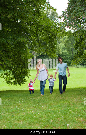 Parents walking with children in park Stock Photo