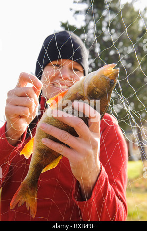 Woman taking out fish from fishing net Stock Photo