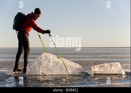 Man skating on frozen lake and looking at ice floe Stock Photo