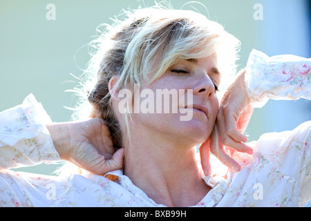 Woman in nightgown stretching with eyes closed Stock Photo
