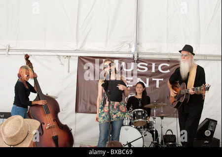 Anglo female sings into microphone accompanied by band mates on stand-up bass, drums and guitar at Texas Book Festival in Austin Stock Photo