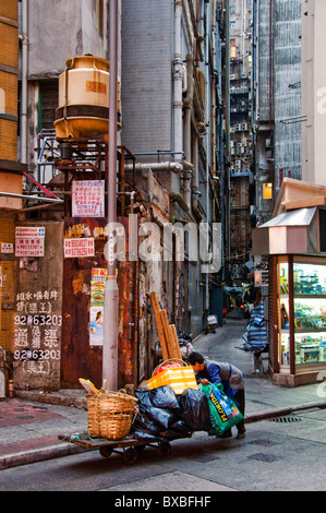 Older Chinese woman pushing cart on street in Hong Kong China Stock Photo