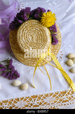 Close-up of straw hat decorated for Easter with purple and yellow dried flowers Stock Photo