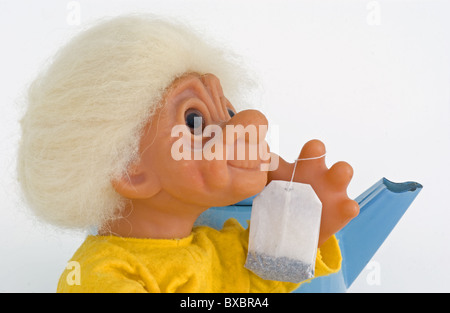 Grandmother figure troll with fresh teabag and teakettle in background is getting ready to make some hot tea. Stock Photo