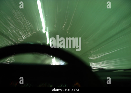 Blurred motion of car moving through a tunnel with steering wheel in foreground Stock Photo