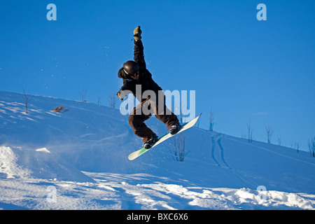Snowboarder jumping in air from ramp surrounded by snow, Arthurs Seat, Edinburgh Scotland UK Europe Stock Photo
