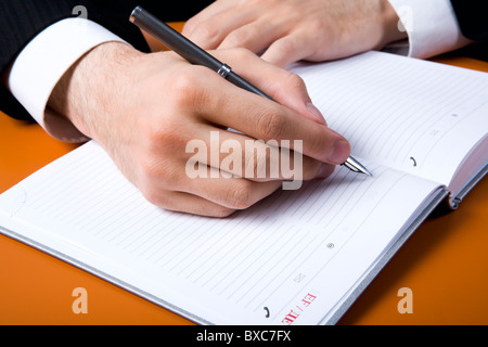 Human hands making notes in pocket- book Stock Photo