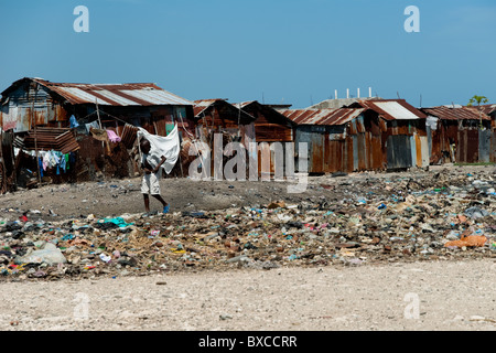 Haitian boy walks in front of shacks in the slum of Cité Soleil. Stock Photo