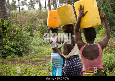 Women carry water back from the well in Masiaka, Sierra Leone, West Africa. Stock Photo