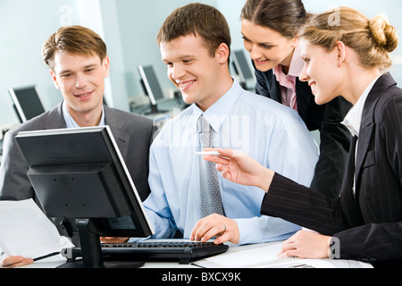 Business group of four people discussing different questions gathered together around the monitor Stock Photo