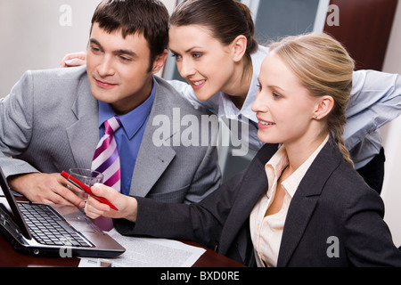 Portrait of three business people looking at a monitor of laptop Stock Photo