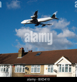 Aeroplane flying over rooftops near Heathrow Airport London UK Stock Photo