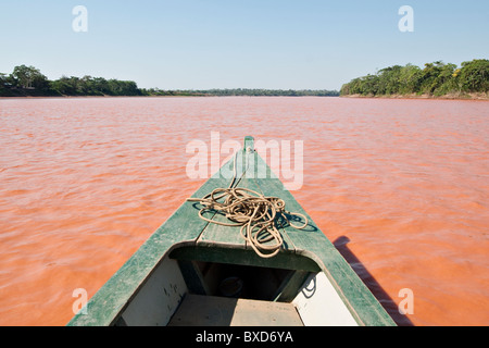 A wooden canoe made of Eucylptus tree floats in the amazon river and connecting tributary rivers in the rainforest. Stock Photo