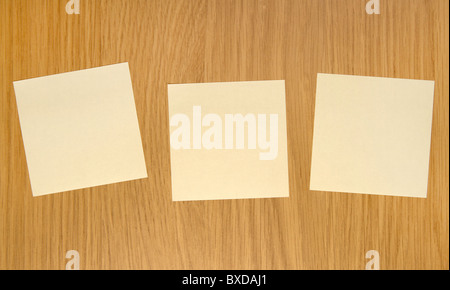 Three yellow sticky notes on wooden door Stock Photo