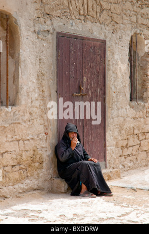 A man sitting in a doorway in the Medina souq market of Essaouira, Morocco Stock Photo