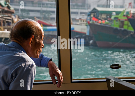 Asian man looking out window of boat in Hong Kong China Stock Photo