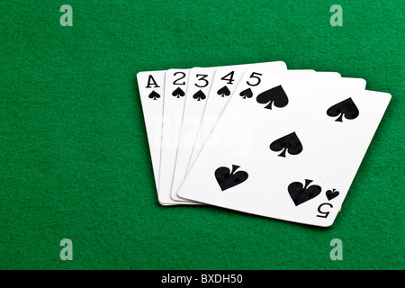 Poker hand with a straith flush of spades on green felt Stock Photo