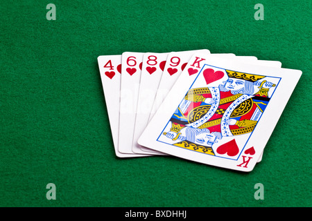 Poker hand with a flush of hearts on green felt Stock Photo