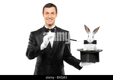 A magician in a black suit holding a top hat with a rabbit in it Stock Photo