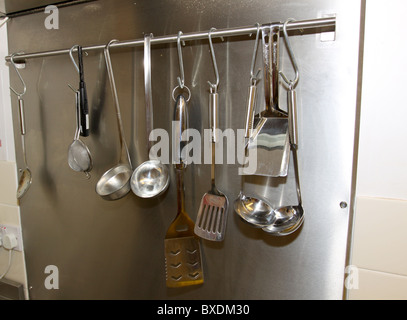 https://l450v.alamy.com/450v/bxdm30/cooking-utensils-hanging-on-rail-in-commercial-kitchen-bxdm30.jpg