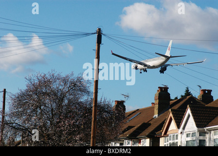 Aeroplane flying over rooftops near Heathrow Airport London UK Stock Photo