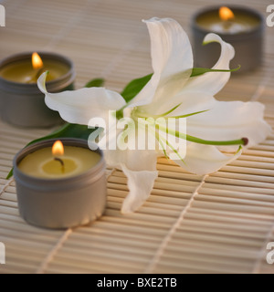 Tea lights and white lily on bamboo mat Stock Photo