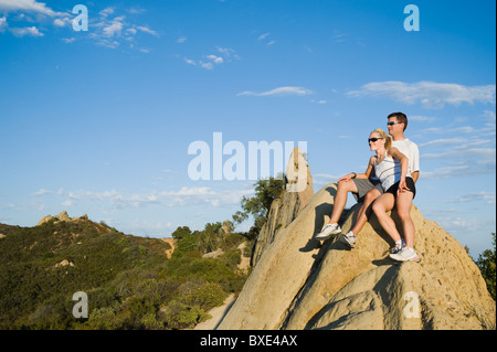 Couple relaxing on peak of rock Stock Photo