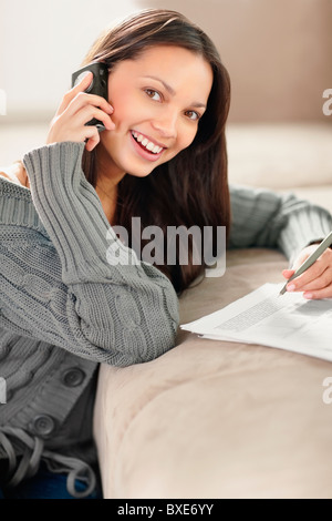 Woman talking on phone while doing paperwork Stock Photo