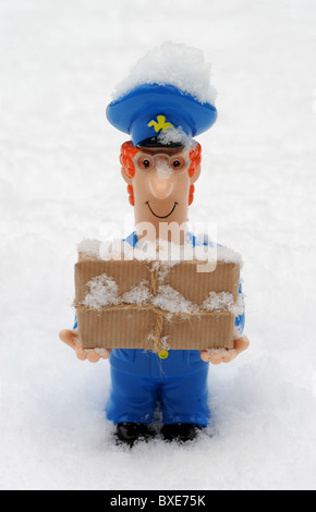 POSTMAN FIGURE WITH PARCEL IN SNOWY ICY  WEATHER CONDITIONS RE POST OFFICE WINTER DELIVERIES DELAYS ETC UK POSTAL SERVICE Stock Photo