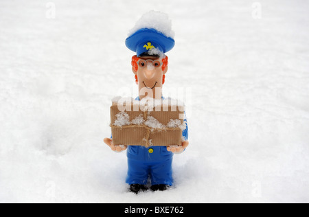POSTMAN FIGURE WITH PARCEL IN SNOWY ICY  WEATHER CONDITIONS RE POST OFFICE WINTER DELIVERIES DELAYS ETC UK POSTAL SERVICE Stock Photo