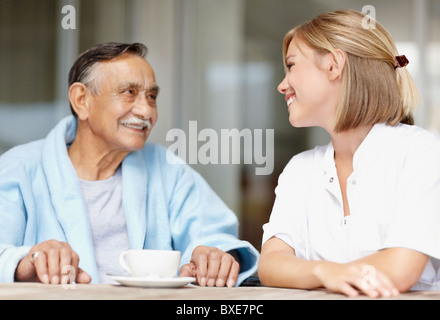 Nurse and senior patient sitting at table Stock Photo