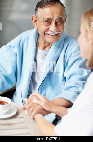 Nurse and senior patient sitting at table Stock Photo