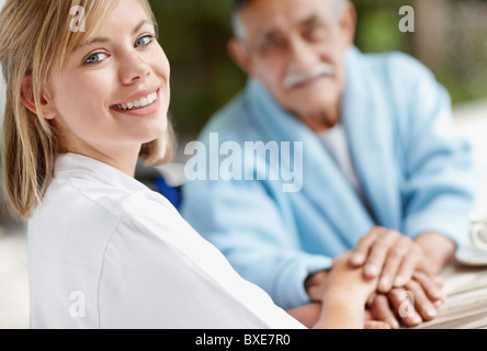 Nurse and senior man holding hands Stock Photo