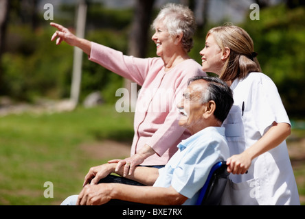 Two woman out for a walk with man in a wheelchair Stock Photo