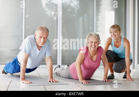 Senior couple exercising with a fitness instructor Stock Photo