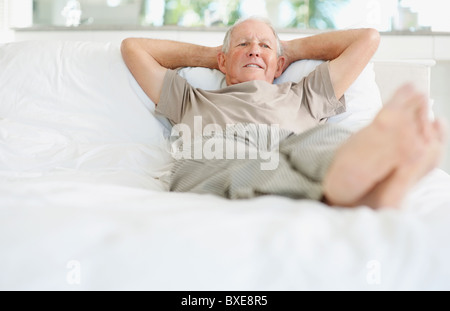 Relaxed senior man lying on bed Stock Photo