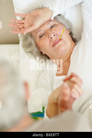 Senior woman with a thermometer in her mouth Stock Photo