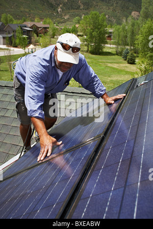 Construction worker installing solar panel on roof Stock Photo