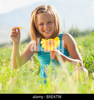 Young girl pulling petals off of gerbera daisy