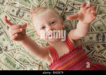 Young girl lying on a pile of money Stock Photo