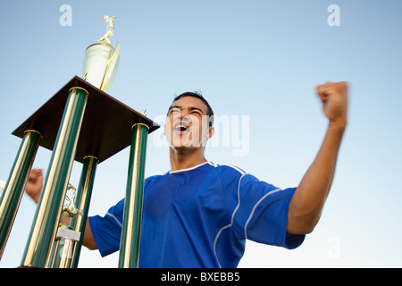 Trophy in front of cheering soccer player Stock Photo