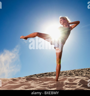 Female dancer kicking her leg on the beach Stock Photo