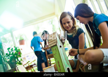 Two girls painting a birdhouse Stock Photo