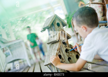 Young boy painting a birdhouse Stock Photo