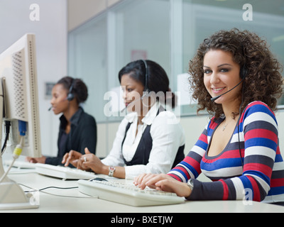 multiethnic group of female customer service representatives talking on the phone, with woman looking at camera. Stock Photo