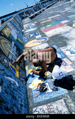 A visiting yachtsman hand-paints a ship's calling card on the marina walls in Horta, Faial island in the Azores Stock Photo