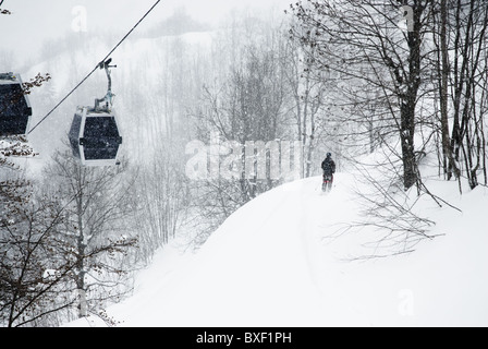 A free skier skiing below cabins on a snowy day at Limone Piemonte, Italy